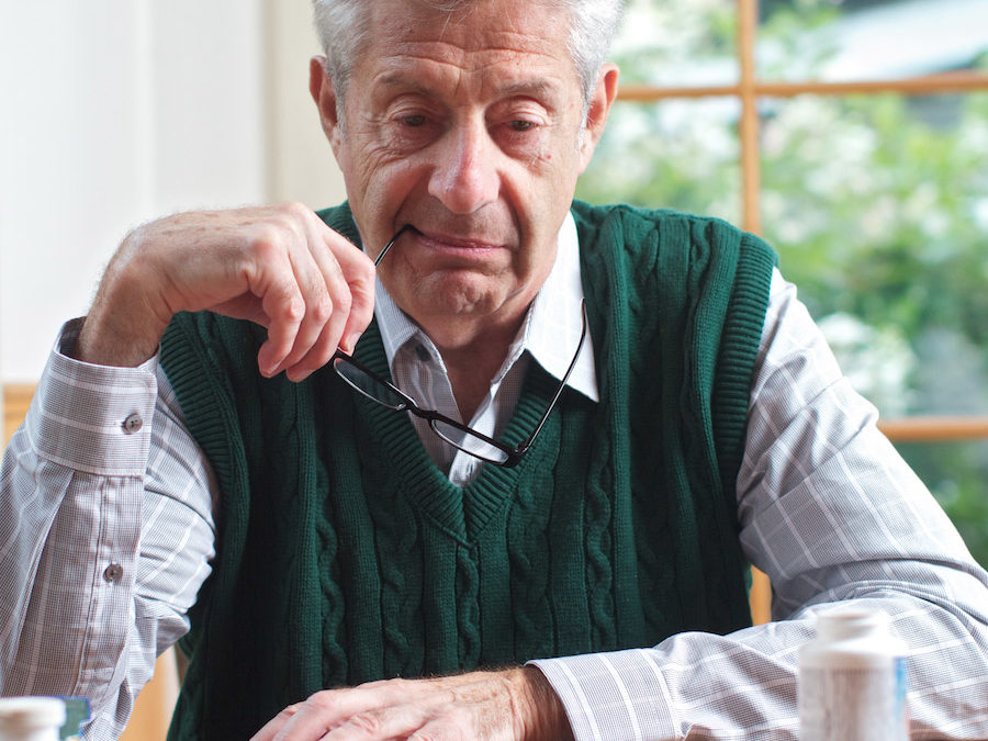 senior looking at his medications