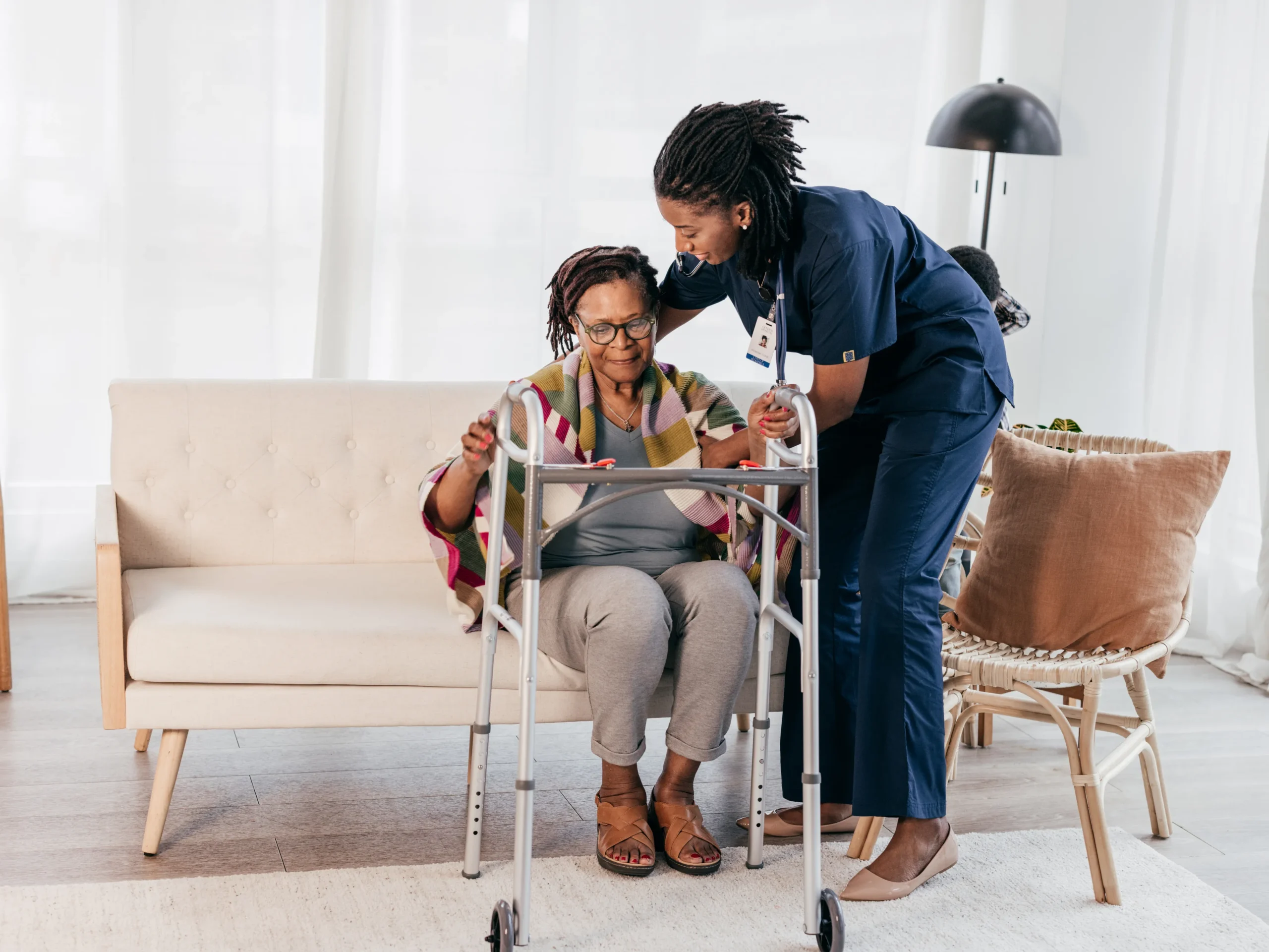 nurse assisting elderly lady with walker