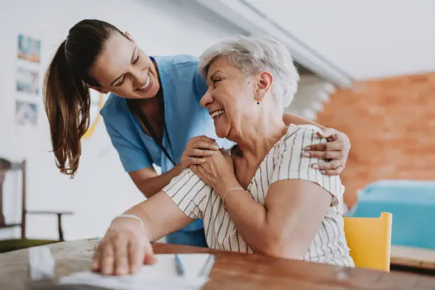 nurse and elderly woman laughing together