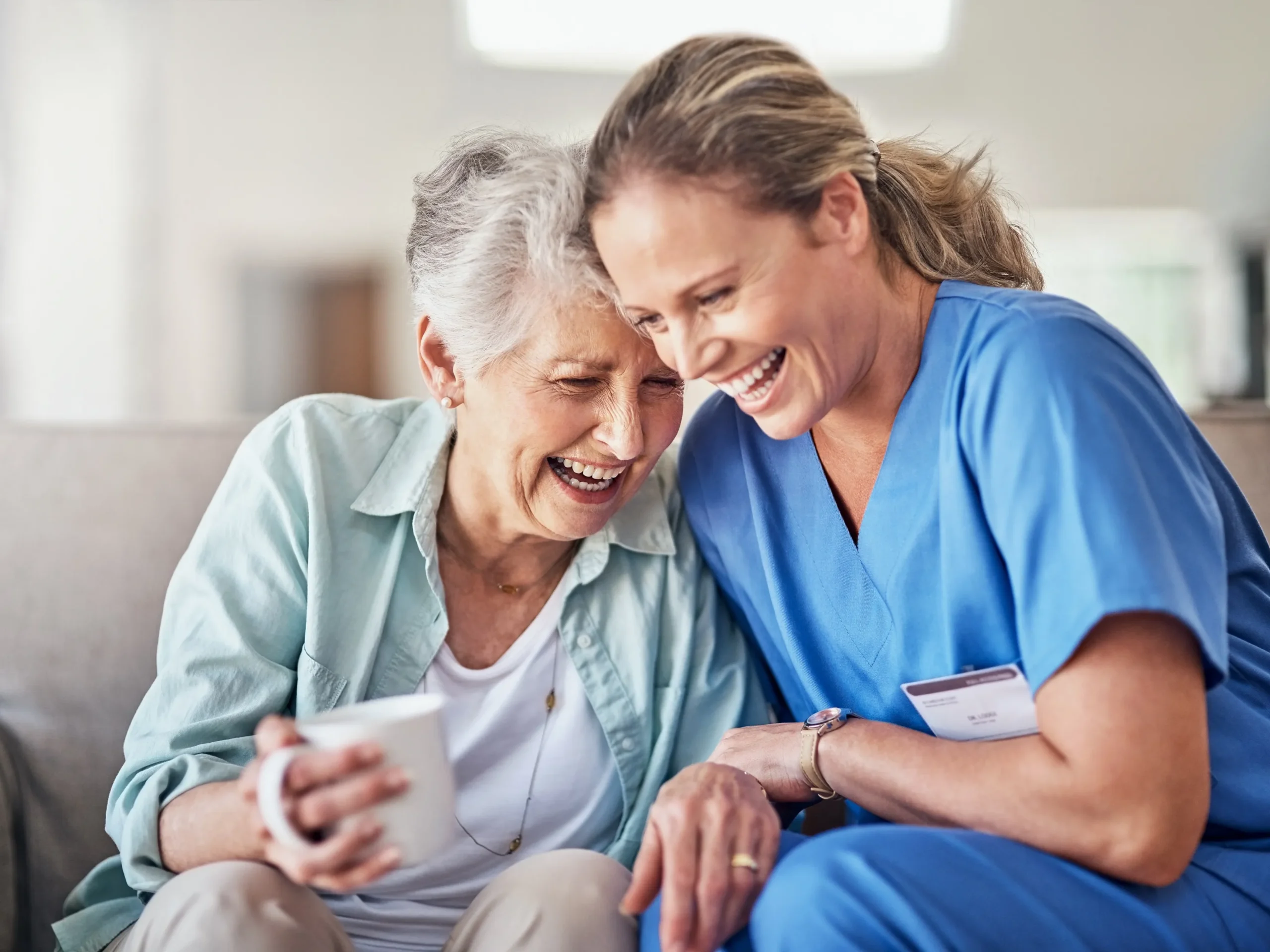 elderly woman and nurse laughing together