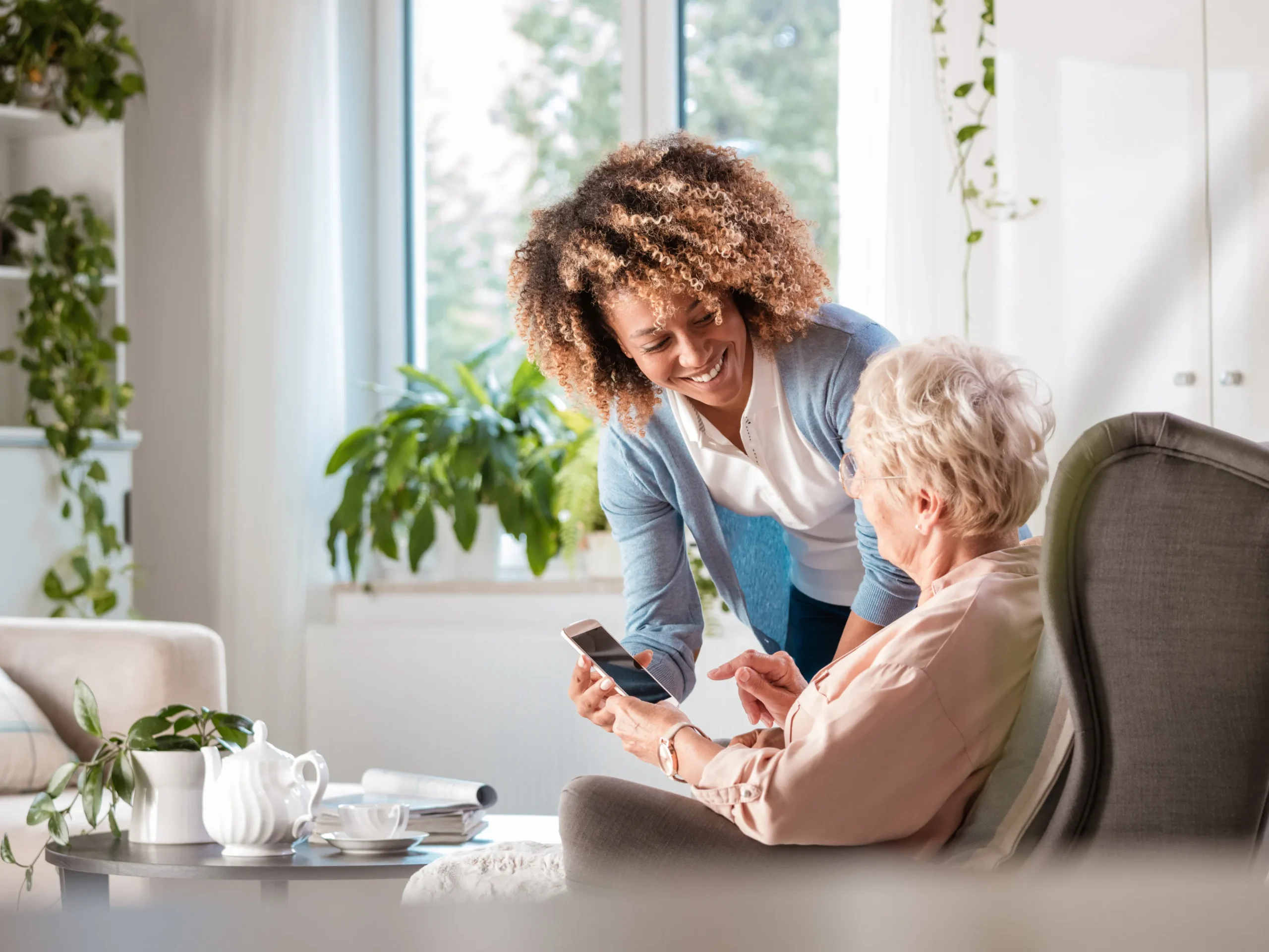 nurse assisting an elderly woman in using a phone